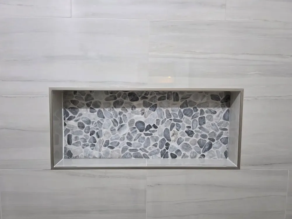 Precision tiled shower niche with pebble mosaic